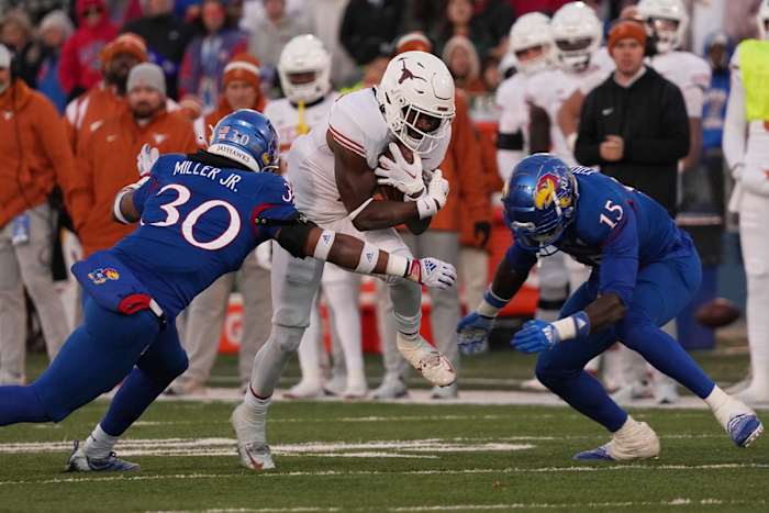 Texas Longhorns running back Keilan Robinson (7) carries the ball as Kansas Jayhawks linebacker Rich Miller (30) and Kansas Jayhawks linebacker Craig Young (15) defend.